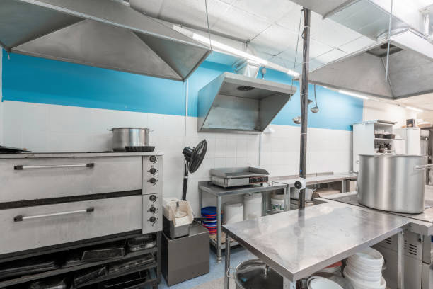 Modern restaurant kitchen with stainless steel kitchenware and equipment. Cooking with preparation tables, pans, pots, stoves